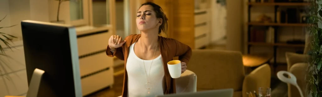 Une femme en télétravail savoure une pause bien méritée autour d'une tasse de café et devant son ordinateur. Elle profite de ce moment de détente pour se ressourcer, offrant un instant de répit dans sa journée de travail à domicile.